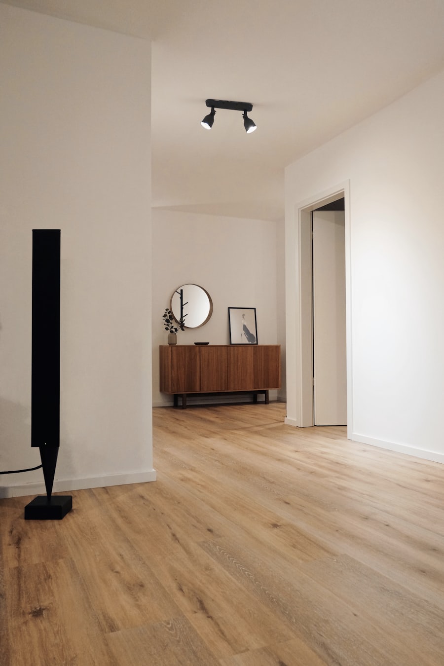 Pièce d'habitation rénovée&nbsp;: murs blancs, sol en bois clair et éclairage sur rail.