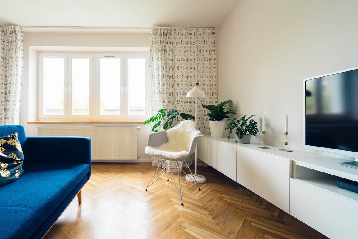 Séjour d'appartement rénové&nbsp;: parquet à bâtons rompus, murs clairs et grande fenêtre.